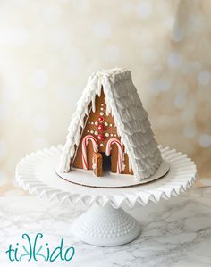 a white plate topped with a gingerbread house covered in icing and candy canes