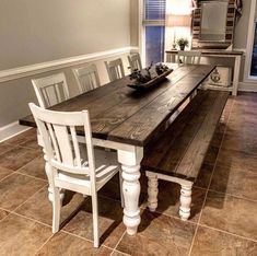 a wooden table with white chairs and a bowl of fruit on it in a dining room