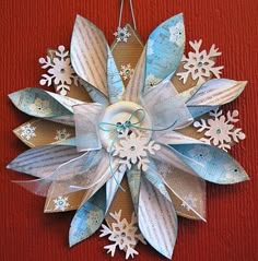 a paper snowflake decoration hanging on a red wall with white and blue ribbons