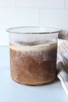 a glass jar filled with liquid sitting on top of a counter next to a towel