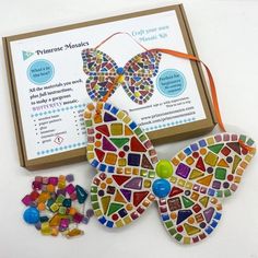 a colorful butterfly ornament sitting next to a box of beads and other crafting supplies