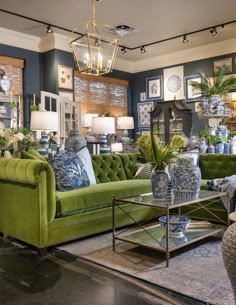 a living room filled with green couches and blue and white vases on top of a coffee table