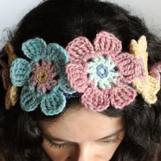 a close up of a person wearing a crocheted headband with flowers on it