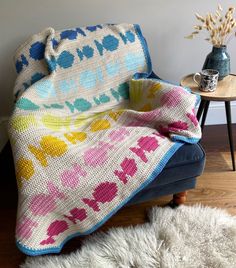 a couch covered in a colorful blanket next to a table with a potted plant