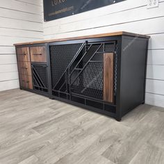 a large black cabinet with wooden doors and metal bars on the bottom, in front of a white wall