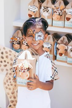 a young boy with his face painted like a giraffe holding a cardboard box