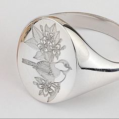 a silver ring with a bird and flowers on it