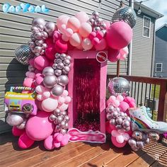 a pink and silver balloon arch on a deck with some balloons in the shape of hearts