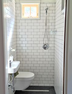 a white toilet sitting in a bathroom next to a sink and shower head mounted on a wall