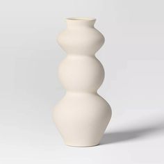 a tall white vase sitting on top of a table