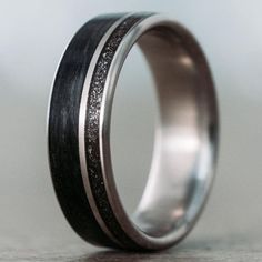 a wedding ring with black and silver inlays on the inside, sitting on a table