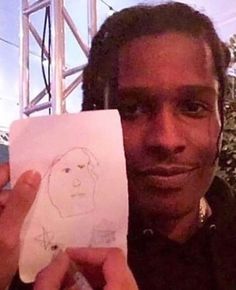 a man holding up a paper with a drawing of a person on it in front of him