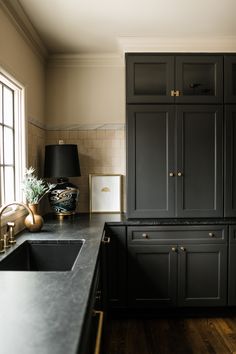 a kitchen with black cabinets and wooden floors