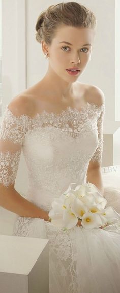 a woman in a white wedding dress holding a bouquet of flowers and posing for the camera