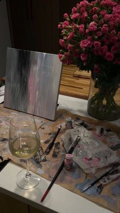 a glass of wine sitting on top of a table next to a painting easel