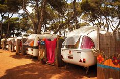 several campers are lined up next to each other in the dirt near trees and bushes