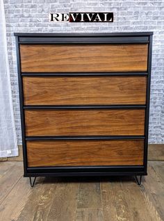 the chest of drawers is made out of wood and black metal, with a brick wall behind it