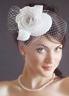 a woman wearing a white veil and flower on top of her head with pearls around it