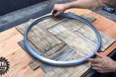 a man is working on a wooden table with a large metal ring in it's center