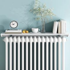 a white radiator next to a shelf with books and a cup on it