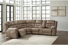 a large sectional couch with recliners in a living room next to two windows