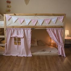 a bed with pink and white curtains on it's sides, next to a wooden floor