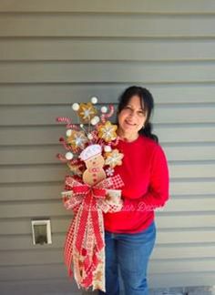 a woman standing next to a wall holding a bouquet of flowers and candy canes