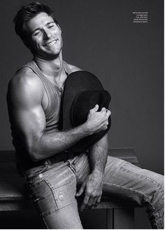 a man sitting on top of a wooden table holding a hat