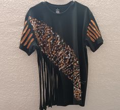 This t-shirt was hand painted and decorated by artist, Jennylynd James and is one of a kind.  ONE SIZE - Fits small, medium, large A T-shirt called "Rip Tide" The abstract image of shapes in bold colours of gold and bronze on a black background are accented with this fringed lower part of the t-shirt. Rip Tide is a bold statement of flare and fun! Great for outdoor events or a night on the town and Suitable for the hot summer weather. It's the perfect companion for jazz, blues, and earth music l Hand Painted Short Sleeve Cotton Top, Hand Painted Cotton Short Sleeve Top, Hand Painted Short Sleeve Graphic Tee, Artistic Hand Painted Short Sleeve T-shirt, Black Cotton T-shirt For Festival, Hand Painted Cotton Graphic Tee, Artsy Black Cotton T-shirt, Casual Hand Painted Cotton T-shirt, Casual Cotton Hand Painted T-shirt