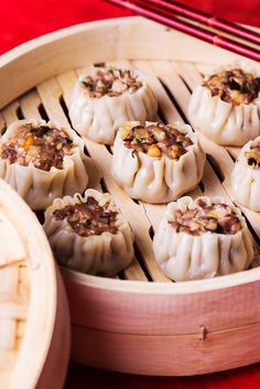 some food that is sitting in a wooden container on a table with chopsticks