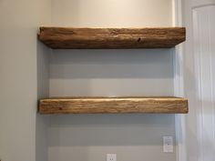 two wooden shelves in the corner of a room with a light switch on one side