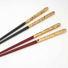 four wooden chopsticks with black and red handles on a white surface, in the shape of snakes