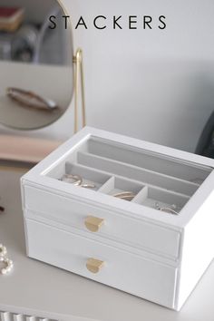 a white jewelry box sitting on top of a table next to a mirror and other items