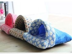 three cat beds are lined up on the floor in front of a vase with flowers