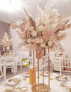 a centerpiece with flowers and feathers on a table in a room decorated for a wedding