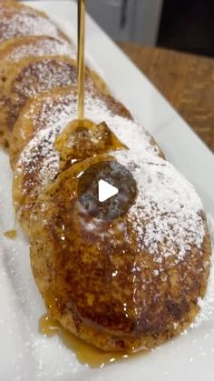 a pancake with syrup being drizzled onto it on a white plate