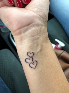 a woman's wrist tattoo with two hearts on the left side of her arm