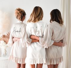 three women in white robes standing next to each other with their hands on their hips