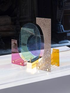 three different colored glass sculptures sitting on top of a white table next to each other