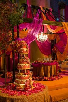 an elaborately decorated wedding cake with pink and orange draping on the side