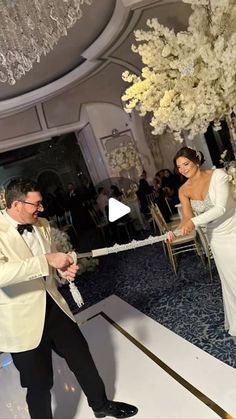 a man and woman in formal wear cutting the ribbon at a wedding reception with an elegant chandelier hanging from the ceiling