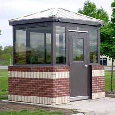 a small red brick building sitting on the side of a road next to a park