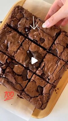 a person pointing at a brownie on top of a tray