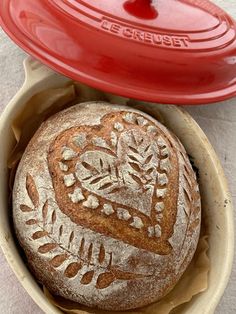 a loaf of bread in a bowl with a red lid