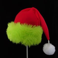 "This festive Santa hat is made up in a red fleece fabric and features an accent brim of a soft lush bright green fur trim, close match to a Grinch green. The red fabric is a soft quality poly fleece fabric, cozy and warm. Proportions of the hat are generous and will fit most head sizes, ladies or gents. The styling is a slouch cone, traditional Santa look. Measurement for opening for your head is 24- 25\" circumference and the length is 20\". There is a white faux fur pompom dangle on the hat." Green Brimmed Winter Costume Hats, Green Winter Costume Hats And Headpieces, Kids Santa Hat, Grinch Hat, Christmas Party Hat, Christmas Party Hats, Green Santa, Red Green Christmas, Green Fur