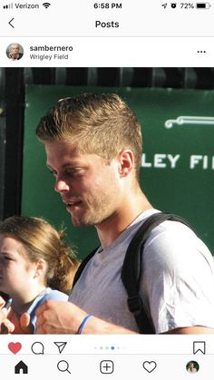 a man looking at his cell phone while standing in front of a green sign with the words valley fire on it