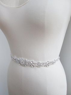 This floral belt design is made with Swarovski crystals set in fancy silver settings. The grosgrain ribbon sash measures 3/8 wide and 140 long. The crystal part of the belt measures 14 long and 1 1/4 wide at the center. Available with grosgrain or satin ribbon and in gold or silver finish. Adjustable Silver Bridal Belt For Wedding, Silver Adjustable Bridal Belt For Wedding, Elegant Silver Belt With Rhinestones, Adjustable Silver Crystal Bridal Belt, Silver Bridal Belt With Sashes For Formal Occasion, Fitted Silver Crystal Bridal Belt, Silver Fitted Bridal Belt For Formal Occasions, Silver Belt With Sashes For Formal Occasions, Silver Crystal Bridal Belt For Wedding