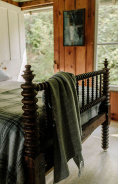 a bed with a green blanket on top of it next to a wooden headboard