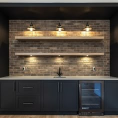 an empty kitchen with brick wall and built - in wine cooler, under cabinet lighting