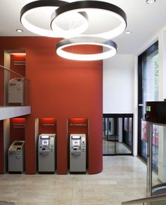 the interior of an office building with red walls and metal atm machines on each wall